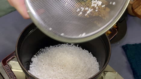 A-Japanese-female-chef-puts-rice-into-a-pot-at-her-home-kitchen,-Tokyo,-Japan