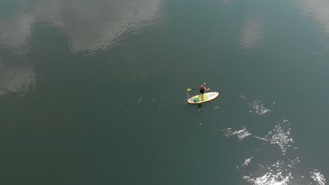 Aerial-birds-eye-view-of-a-blonde-woman-on-a-stand-up-paddle-board-on-the-river-Nile