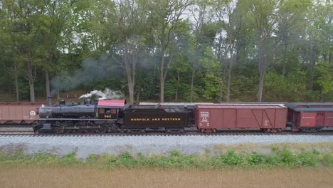 Aerial-View-of-a-Steam-Locomotive-Passenger-Train-Slowly-Pulling-on-a-Siding-Passing-a-Steam-Freight-Train-with-Smoke-and-Steam
