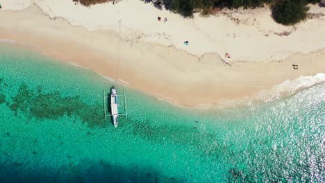 Antigua,-white-sand-beach,-turquoise-water-and-small-boat-floating-in-the-clear-sea