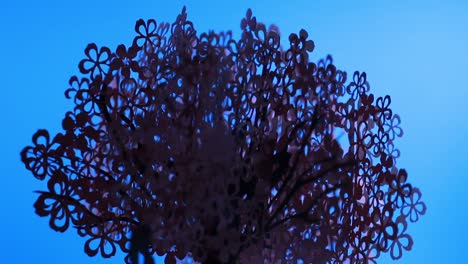 Beleuchteter-Rosafarbener-Papierbaum,-Der-Sich-Auf-Blauem-Hintergrund-Dreht