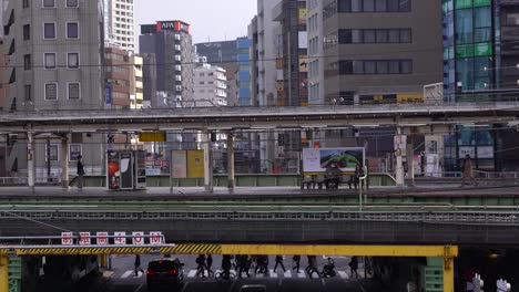 Heavy-road-traffic-under-the-train-overpass-in-Tokyo,-Japan---medium-shot