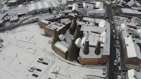 Aerial-view-of-the-famous-bottle-kilns-at-Gladstone-Pottery-Museum,-covered-in-snow-on-a-cold-winter-day-after-a-sudden-snow-blizzard,-Pottery-manufacturing,-snow-in-Stoke-on-Trent