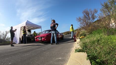 Pit-Crews-Checking-The-Racing-Cars-Stopping-By-The-Pit-Stop-At-The-Hill-In-Imtahleb-Malta-On-A-Sunny-Day---GoPro-Timelapse