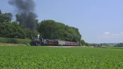 A-1924-Steam-Engine-with-Passenger-Train-Puffing-Smoke-Traveling-Along-the-Amish-Countryside-on-a-Summer-Day