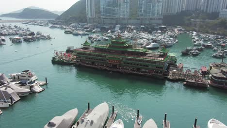Jumbo-floating-restaurant-in-Hong-Kong-Aberdeen-Harbour-typhoon-shelter,-Aerial-view-with-skyscrapers-in-the-background-and-boats