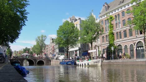 Boats-with-Tourists-About-to-Begin-a-Guided-Tour-Through-the-Canals-in-Amsterdam-in-the-Summer,-Netherlands