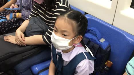 Asian-student-child-girl-going-to-school-in-the-morning,-wearing-a-medical-mask,-taking-subway-or-MRT-of-Thailand