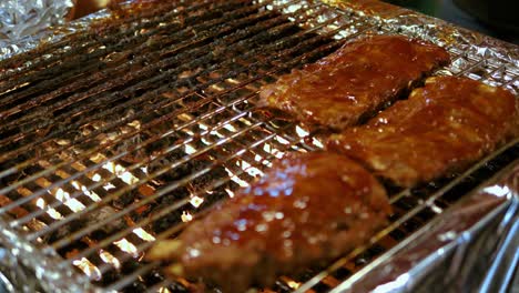 Close-up-Ribs-with-sauce-on-barbecue-grill-food-night-market,-Bangkok