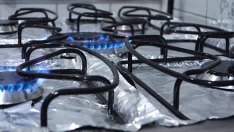 domestic-kitchen-burners-turning-on-in-sequence,-with-blue-flame