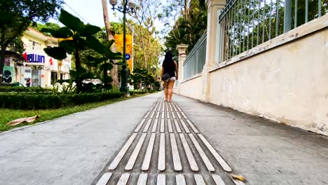 Back-View-Of-A-Saigon-Woman-Walking-On-The-Pathway-In-Ho-Chi-Minh,-Vietnam---slowmo-dolly-shot
