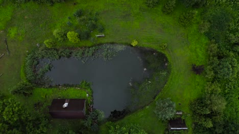 Aerial-of-pond-next-to-country-house-in-greenery-in-the-summer
