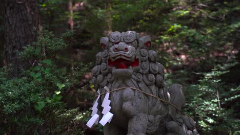 Menacing-and-scary-ancient-Japanese-lion-statue-in-temple-inside-forest---locked-off-view