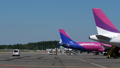 Aviones-De-La-Aerolínea-Wizzair-Estacionados-Y-Revisados-Por-Los-Trabajadores-En-La-Plataforma-Del-Aeropuerto-De-Eindhoven-En-Eindhoven,-Países-Bajos