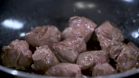 Pieces-of-Meat-Sizzling-Gold-Brown-in-Non-Stick-Black-Pan---Close-Up