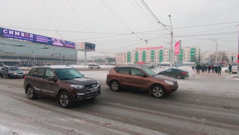 Cars-and-tram-driving-along-Revolutionary-street-in-Ufa,-Russia-during-blizzard