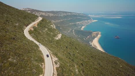 Aerial-view-over-Arrábida-beach-in-Setubal,-Portugal-cars-driving