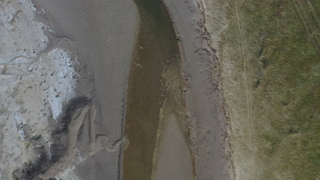 Aerial-top-down-view-showing-a-water-trench-in-a-coastal-bay-at-low-tide