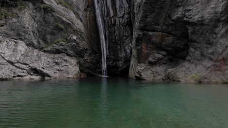 Unberührter-Bergsee-Mit-Wasserfall,-Wasser,-Das-In-Einen-Tiefen,-Dunklen-Abgrund-Fällt