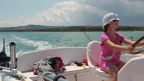 Kleines-Mädchen-Mit-Sonnenbrille-Und-Hut-Fährt-Motorboot