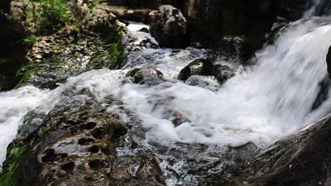 Wasser,-Das-Sanft-Aus-Einem-Kleinen-Bachbett-Fließt,-über-Felsen-Geht-Und-Dann-Weiter-über-Eine-Andere-Kante-Fällt