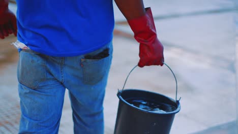 Male-Worker-With-Rubber-Gloves-Carrying-A-Bucket-With-Acid-For-Pool-Cleaning---close-up