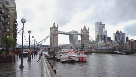 London-Cityscape,-England-UK,-Tower-Bridge,-Riverwalk-by-Thames-River,-Downtown-Skyscrapers-Under-Cloudy-Sky,-Slow-Motion-Panorama