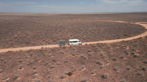 Aerial-view-of-a-van-and-a-trailer,-sunny-day-on-a-desert---tracking,-drone-shot