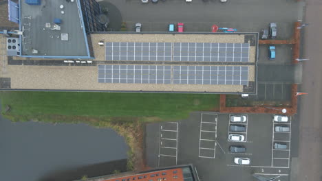 Top-down-aerial-of-solar-panels-on-office-building-rooftop---drone-setting-down
