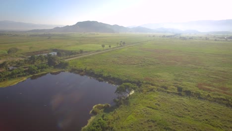 Drone-shot-of-a-lake-in-the-countryside-field-with-some-mist