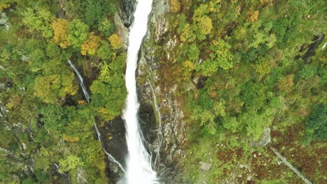 Idyllic-Snowdonia-mountain-range-Aber-falls-waterfalls-national-park-aerial-view-birdseye-tilting-down