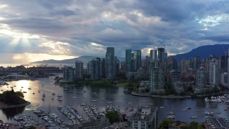 Stimmungsvoller-Sonnenuntergang-Mit-Sonnenstrahlen,-Die-Zwischen-Den-Wolken-Ihren-Höhepunkt-Erreichen---Drohnenluftaufnahme-über-Dem-Yachthafen-Von-Vancouver