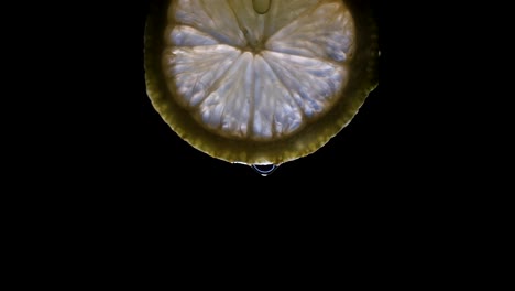 A-pulsing-light-lights-up-a-lemon-slice-isolated-on-a-black-background