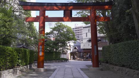 Typical-Japanese-red-Torii-gate-at-entrance-of-Nezu-Shrine-in-Tokyo,-Japan-with-residential-area-in-backdrop