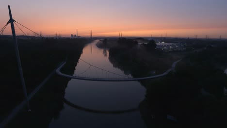 Aerial-view-of-suspension-bridge-above-the-river-during-sunset
