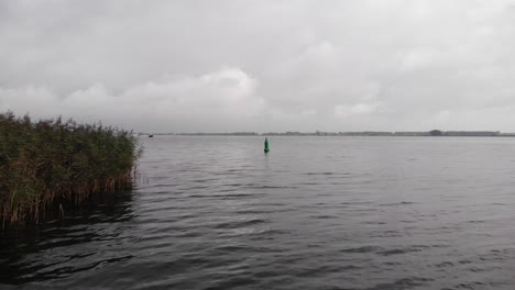 Boya-Náutica-Verde-Flotando-En-El-Agua-Marcando-Un-Canal-Para-Barcos-En-Un-Día-Nublado