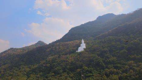 Luang-Por-Khao,-Wat-Theppitak-Punnaram,-aerial-4k-reverse-footage-of-the-famous-Giant-White-Buddha-during-the-afternoon,-birds-flyby,-beautiful-sky-with-dramatic-clouds