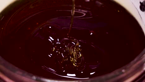 Thick-Dark-Honey-Drizzling-Back-into-Container,-Extreme-Closeup