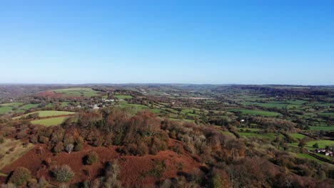 Antena-Girando-En-Círculos-Dumpdon-Hill-Mirando-Hacia-El-Cielo-Azul-Y-Los-Campos-Verdes-De-East-Devon,-Inglaterra
