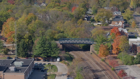 Aerial-view-of-bridge-over-train-tracks-in-small-town-USA-in-the-Fall-with-descent