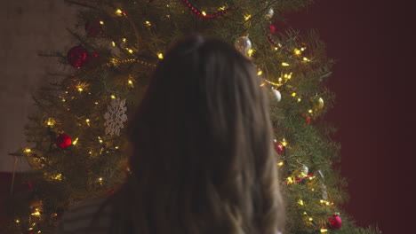 Woman-looking-at-a-christmas-tree
