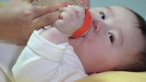 Bebé-Hambriento-Acostado-Boca-Arriba-Alimentando-Leche-En-Botella-Sostenida-Por-Su-Madre