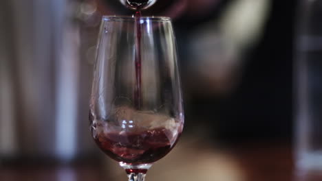 Red-wine-pouring-into-glass-on-restaurant-background