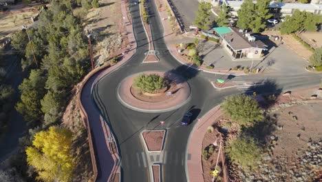 Aerial-tracking-shot-of-navy-blue-BMW-on-roundabout-in-Sedona,-Arizona,-USA