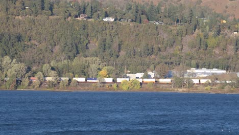 Cargo-train-cars-are-running-by-Columbia-River-shore-near-Hood-River,-USA