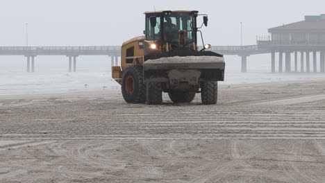Caterpillar-930M-wheel-loader-moving-a-bucket-of-sand-on-White-Cap-Beach-on-North-Padre-Island-on-a-foggy-morning