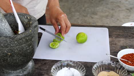 Woman-with-Kitchen-knife-slicing-lime-on-white-board---Outdoor-Kitchen