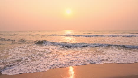 Goldener-Sonnenuntergang-An-Einem-Strand---Zeitlupe-Von-Schaumigen-Wellen,-Die-Unter-Tiefem-Sonnenlicht-In-Richtung-Weißen-Sandstrand-Rollen