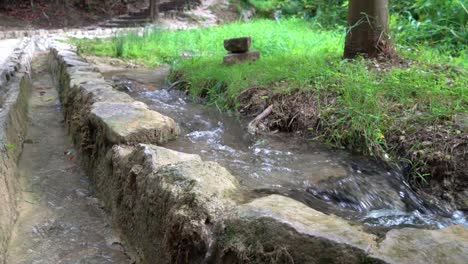 Agua-Que-Fluye-Junto-A-Un-Muro-De-Piedra-A-Lo-Largo-De-Una-Pasarela-En-El-Parque-Nacional-Krka-En-Croacia-A-¼-De-Velocidad