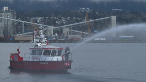 A-Fireboat-Spraying-Water-Fountain-While-Moving-Slowly-By-The-Seaport---Medium-Shot,-Slow-Motion